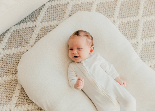 Newborn baby wrapped in a white blanket lying on a textured surface